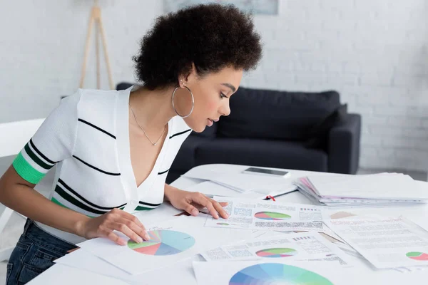 Vista laterale della donna afro-americana che guarda i grafici a casa — Foto stock