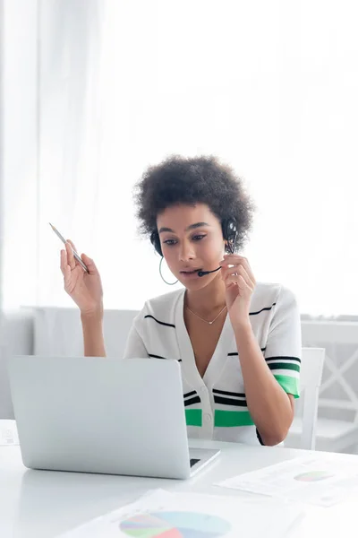 Afro-americano mulher no fone de ouvido ter vídeo chamada no laptop em casa — Fotografia de Stock