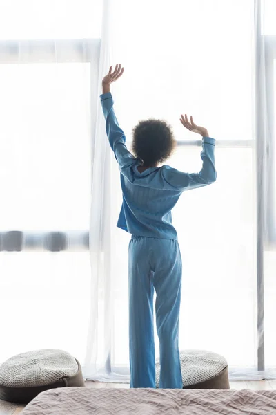 Rückenansicht einer Afroamerikanerin, die sich im Schlafzimmer dehnt — Stockfoto