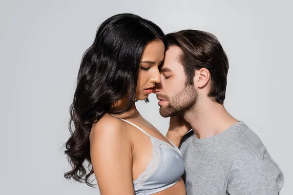 Man with closed eyes near sexy woman in satin bra isolated on grey — Stock Photo