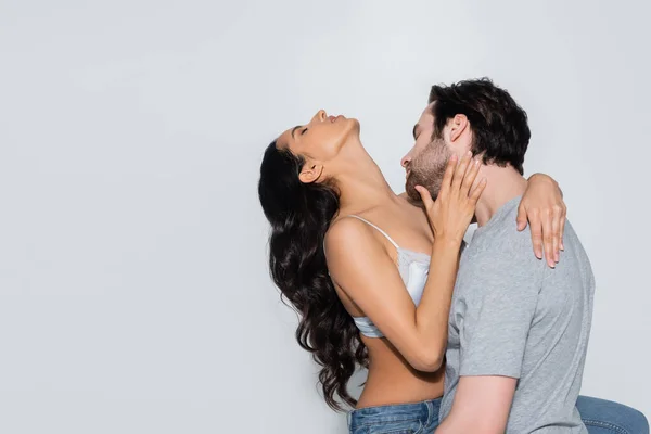 Young man hugging sexy brunette woman with closed eyes isolated on grey — Stock Photo