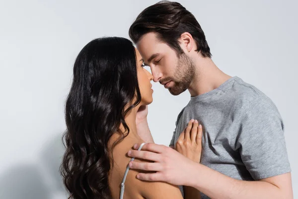 Young man in t-shirt hugging sexy brunette woman in bra on grey — Stock Photo