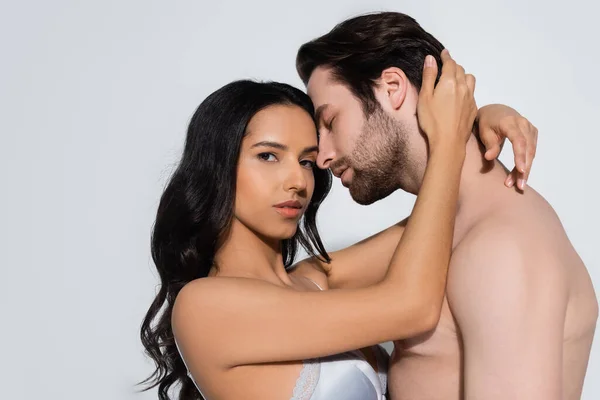 Passionate woman in bra hugging shirtless man isolated on grey — Stock Photo