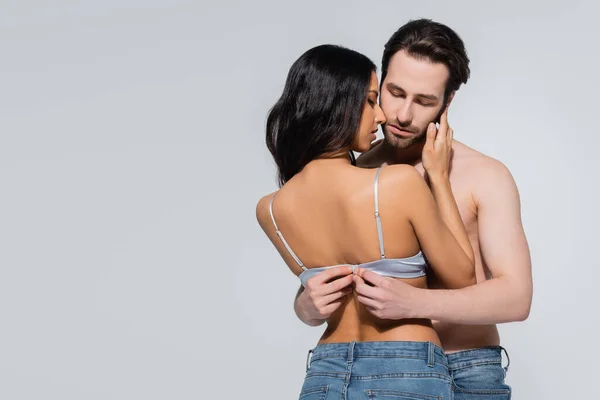 Young shirtless man unfastening bra of sexy woman isolated on grey — Stock Photo