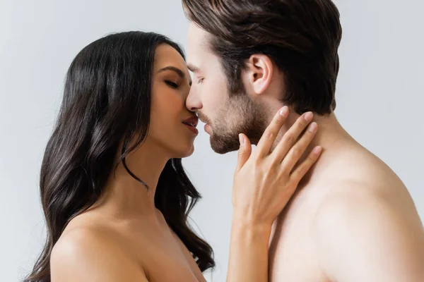 Morena desnuda y hombre besándose con los ojos cerrados aislados en gris - foto de stock