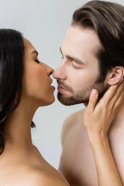 Vista de cerca de pareja joven besándose con los ojos cerrados aislados en gris - foto de stock