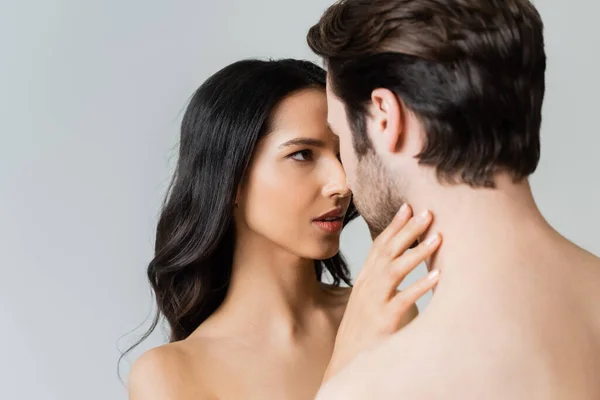 Jolie femme touchant cou de jeune homme torse nu isolé sur gris — Photo de stock