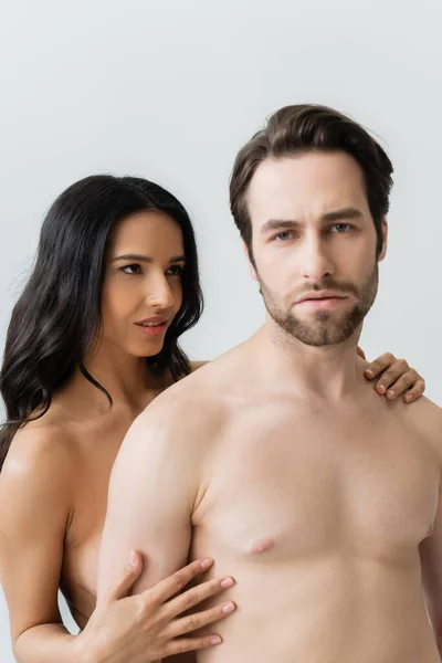 Sexy brunette woman embracing shirtless man looking at camera isolated on grey — Stock Photo