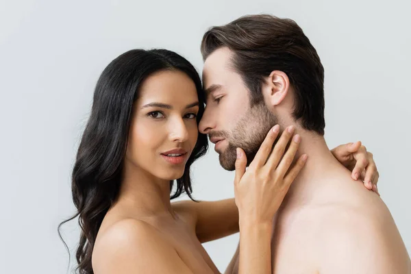 Giovane e sensuale donna guardando la fotocamera mentre abbraccia l'uomo barbuto isolato sul grigio — Foto stock