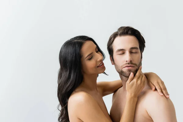 Smiling naked woman touching face of young man isolated on grey — Stock Photo