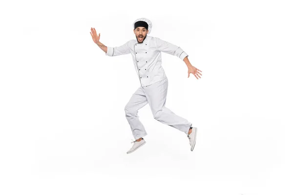 Chef excitado en sombrero y salto uniforme aislado en blanco - foto de stock