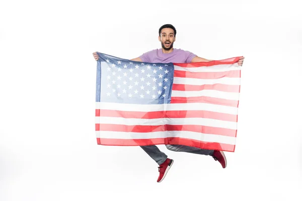 Positiver und patriotischer Mann springt mit amerikanischer Flagge auf weißem Grund — Stockfoto