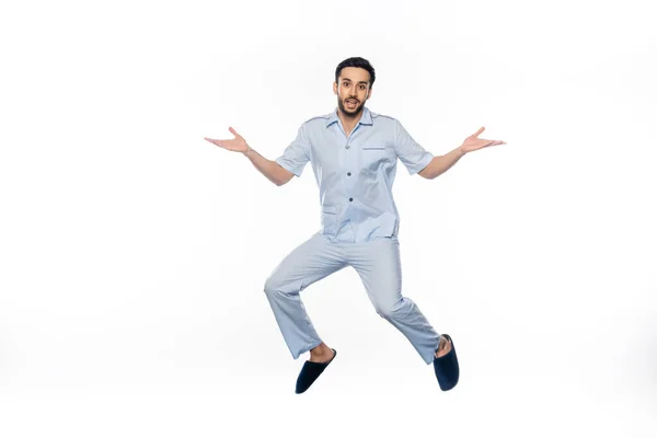 Bearded man in pajamas levitating while gesturing on white — Stock Photo