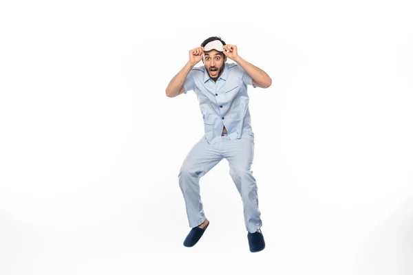 Amazed man in pajamas and sleeping mask levitating on white — Stock Photo