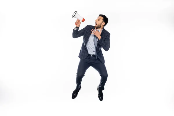 Sorprendido hombre de negocios en traje saltando y sosteniendo el altavoz en blanco - foto de stock