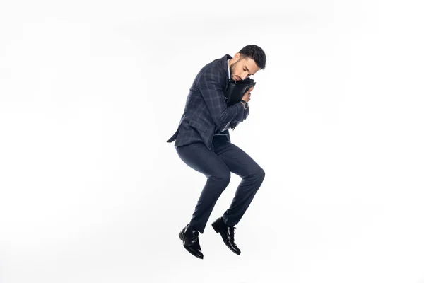 Businessman in suit jumping while hugging briefcase on white — Stock Photo