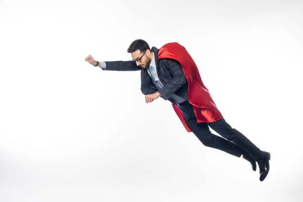 Homme d'affaires en costume, lunettes et cape de super-héros lévitant sur blanc — Photo de stock