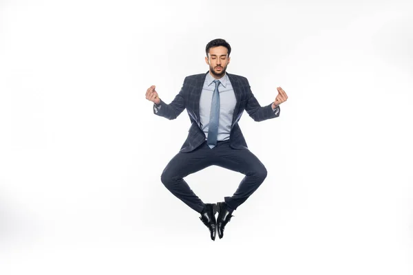 Geschäftsmann im Anzug schwebt und meditiert über Weiß — Stockfoto