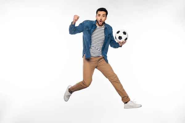 Hombre preocupado levitando mientras sostiene la pelota de fútbol y animando a blanco - foto de stock