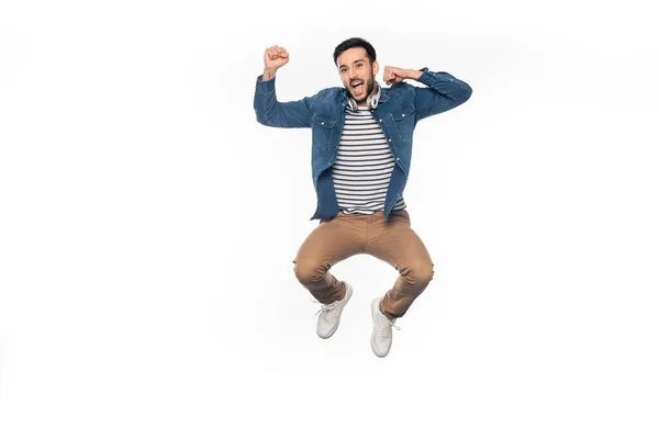 Homme heureux avec casque sans fil lévitant et acclamant isolé sur blanc — Photo de stock