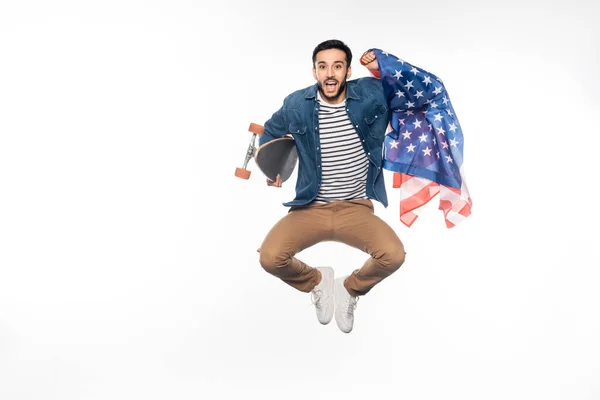 Hombre feliz levitando mientras sostiene longboard y bandera americana en blanco - foto de stock
