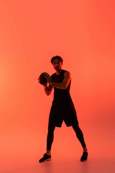 Esportista segurando bola de rugby no fundo vermelho — Fotografia de Stock