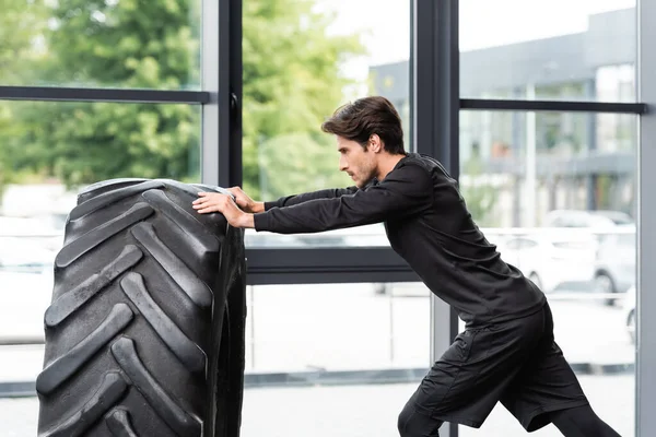 Vue latérale de l'entraînement sportif avec pneu dans la salle de gym — Photo de stock