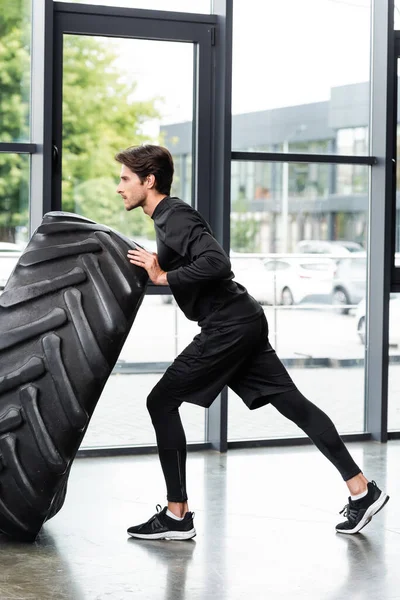 Side view of sportsman working out with tire in sports center — Stock Photo