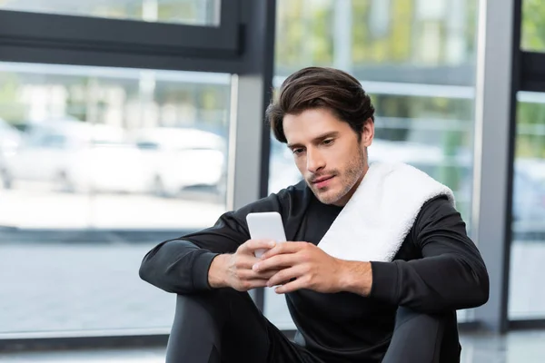 Brunette sportif avec serviette en utilisant le téléphone portable dans le centre sportif — Photo de stock