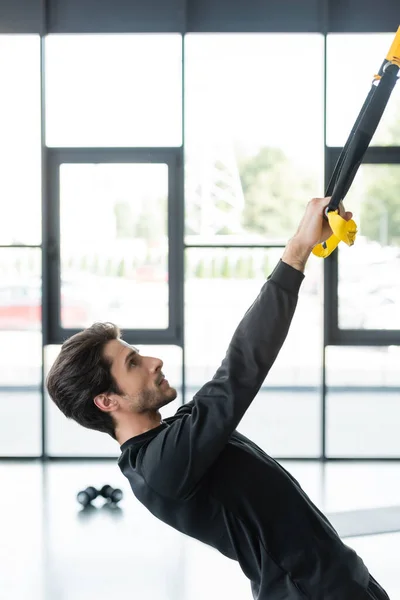 Vista lateral da esportista trabalhando com alças de suspensão no ginásio — Fotografia de Stock