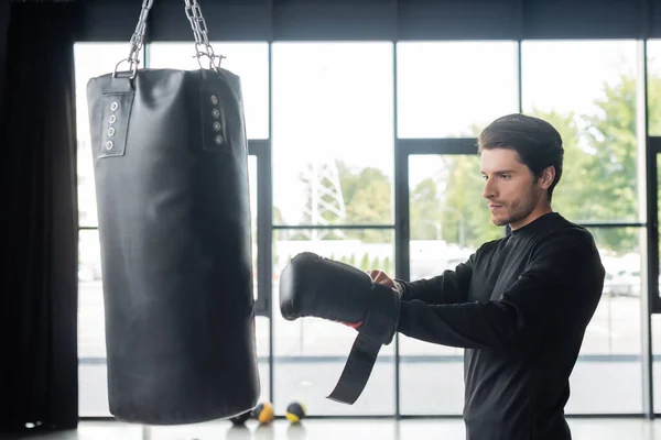 Brunette boxer wearing glove near punching bag in sports center — Foto stock