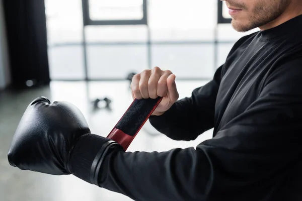 Cropped view of man in sportswear wearing boxing glove in gym — Stockfoto
