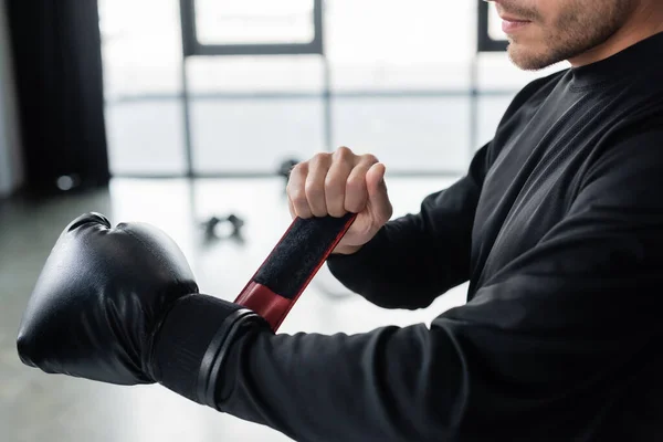 Cropped view of man in sportswear wearing boxing glove in gym — Stock Photo