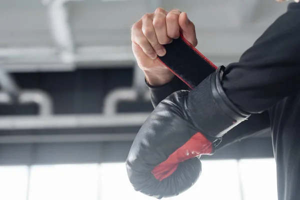 Cropped view of man wearing boxing glove in sports center — Stock Photo