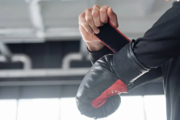 Vista ritagliata dell'uomo che indossa un guanto da boxe nel centro sportivo — Foto stock