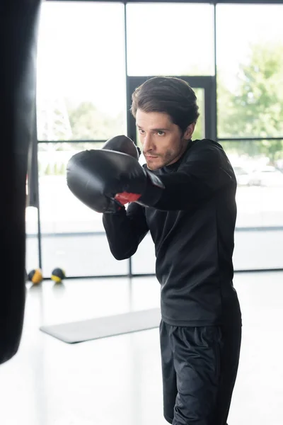 Boxeador morena haciendo ejercicio con saco de boxeo en el centro deportivo - foto de stock