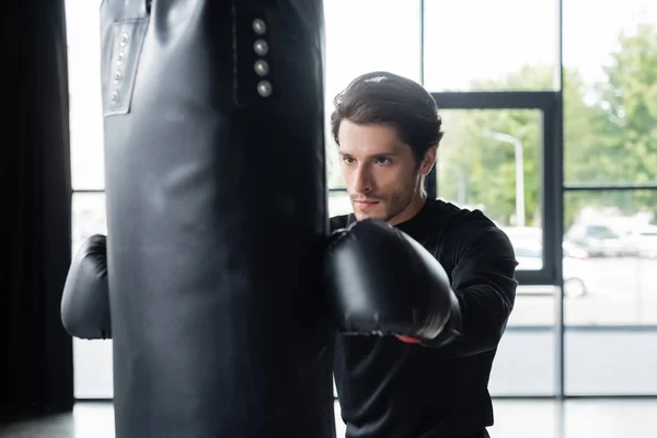 Sportsman dans l'entraînement des gants de boxe avec sac de boxe dans le centre sportif — Photo de stock