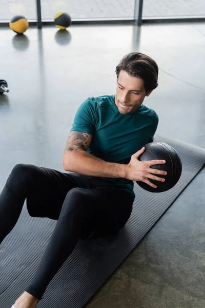 Allenamento sportivo bruno con palla slam sul tappeto fitness nel centro sportivo — Foto stock