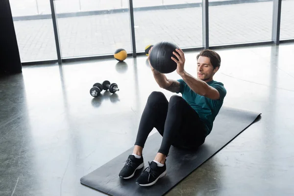 Sportsman working out with slam ball on fitness mat in sports center — Stockfoto