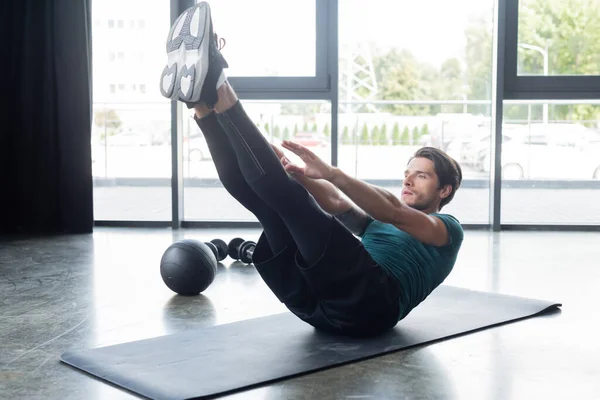 Entrenamiento de deportista atlético en colchoneta de fitness cerca de slam ball en gimnasio - foto de stock