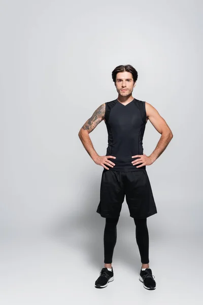 Full length of tattooed sportsman looking at camera on grey background — Stockfoto