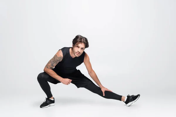Brunette tattooed sportsman working out on grey background — Stock Photo