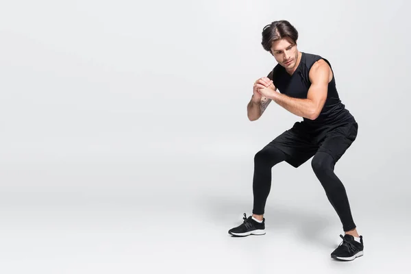 Deportista tatuado en entrenamiento de ropa deportiva negra sobre fondo gris - foto de stock