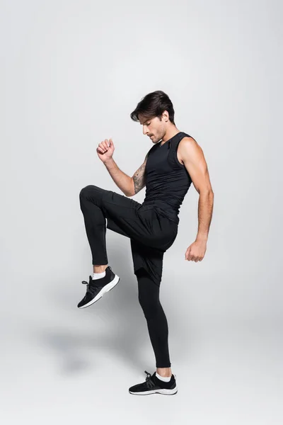 Side view of brunette sportsman training on grey background — Foto stock