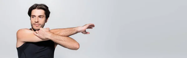 Брюнетка спортсмен растягивая руки изолированы на сером, баннер — стоковое фото