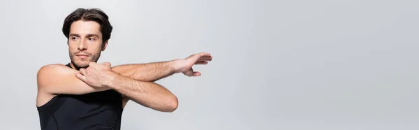 Morena deportista estirando los brazos aislados en gris, bandera — Stock Photo