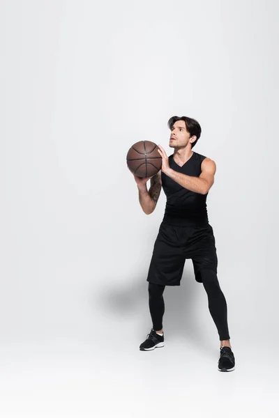 Esportista em sportswear preto jogando basquete em fundo cinza — Fotografia de Stock