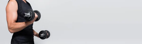 Cropped view of sportsman training with dumbbells isolated on grey, banner — Stock Photo