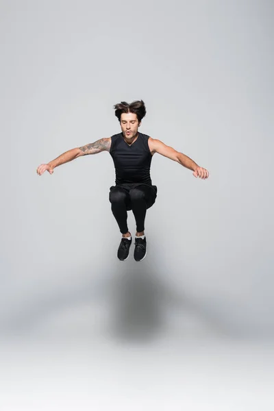 Brunette sportsman jumping on grey background — Stock Photo