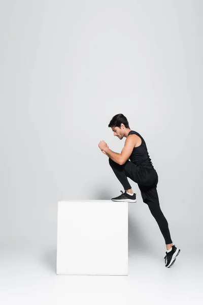 Vista lateral del entrenamiento deportivo con cubo sobre fondo gris - foto de stock